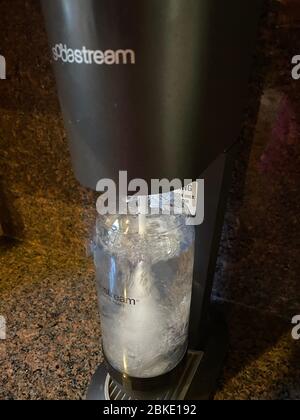 Making sparkling water with a SodaStream machine which adds carbonation to plain water. Consumers can use this to help eliminate single use plastics. Stock Photo