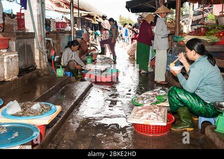 Hoi An Vietnam October 19 2013; Typical wet markets  in Asian city with vendors preparing their offerings and waiting for customers while one woman si Stock Photo