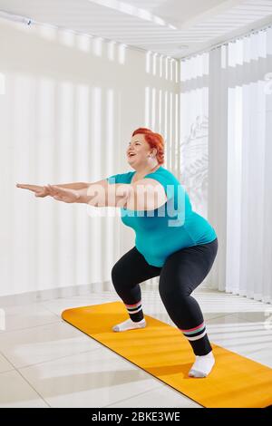 fat cheerful woman doing yoga in the park, plus size model Stock Photo