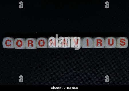 Wooden orange and white letters dice forming the writing "CORONAVIRUS" on a black background. Corona virus danger news. Stock Photo