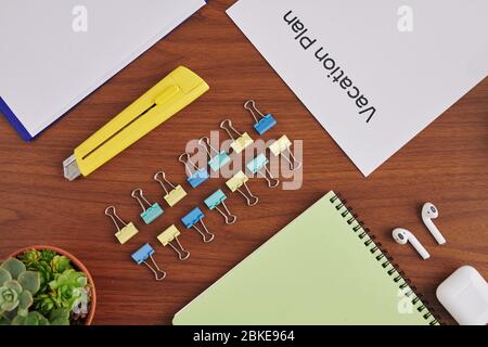 Modern desk of business person with paper clips, paper cutter, vacation plan and other office items Stock Photo