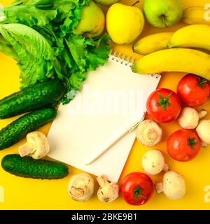 Open recipe book with set of raw organic vegetables on yellow background, copy spae for text Stock Photo