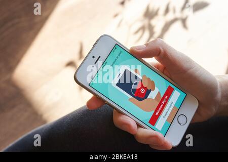 A woman using the Target mobile app from her phone to shop online at home. Stock Photo