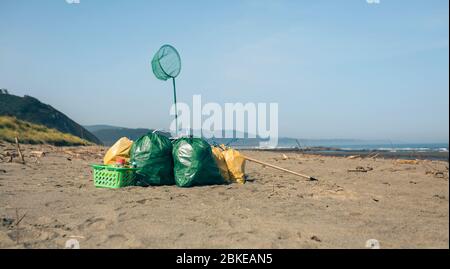 Garbage bags and utensils on the beach Stock Photo
