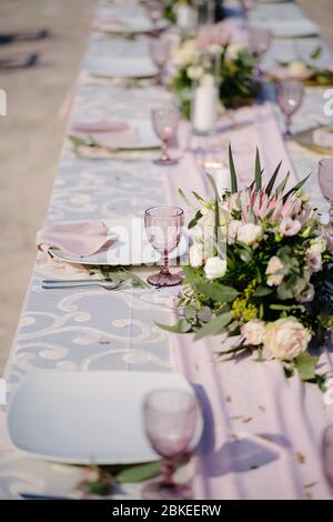 Close-up of a wedding dinner table. Table decoration in pink and white style - serving with white plates with pink glasses, napkins and dining path Stock Photo