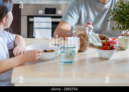 Family breakfast in the kitchen. Girl with father eat healthy breakfast. Stock Photo