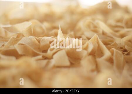 Preparing fresh homemade pasta: macro close-up view handmade fresh tagliatelle just rolled and cutter out with bokeh effect Stock Photo