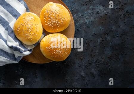 Three isolated fresh homemade burger breads on a dark blue background Stock Photo