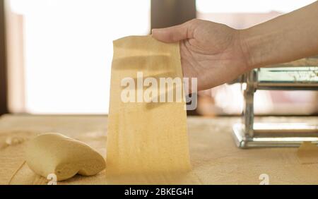 Making homemade fresh pasta: backlit woman hand show the transparency of the just rolled out fresh pasta Stock Photo