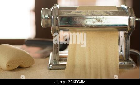 Making homemade fresh pasta: backlit close up of the details of the pasta rolled out by the metal manual pasta machine Stock Photo