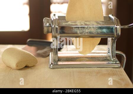 Making homemade fresh pasta: backlit close up of the details of the pasta rolled out by the metal manual pasta machine Stock Photo