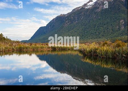 Mirror Lakes in Fiordland National Park, New Zealand. Picturesque landscape with mountain and colourful sky reflections on the water. Stock Photo