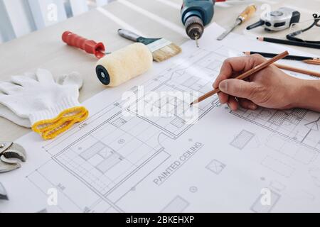 Construction engineer making final corrections in building blueprint or checking size of every detail Stock Photo