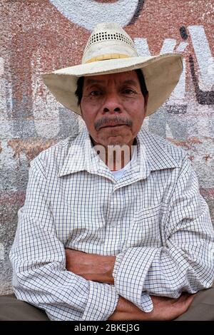 Portrait of middle-aged man with cowboy hat sitting at the door of his house in Amatenango del Valle. Stock Photo