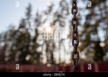 A rusty chain amid the sun and sky. Stock Photo