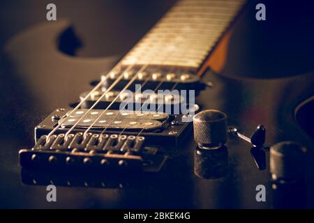 Closeup pickup of the guitar makes the sound amplified louder when connected to speaker. Black vintage electric guitar in dark. Concept of good memory Stock Photo
