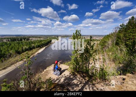 Vedenshina, Russia - April 29, 2020: Young mother shows her child a beautiful landscape in spring Irkut river with sky clouds. View from above Stock Photo