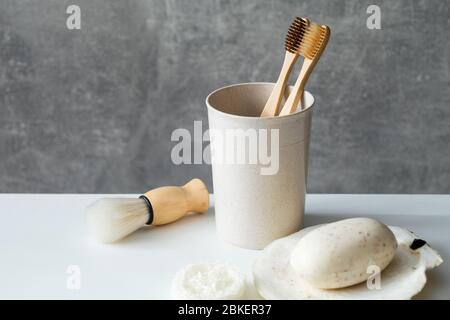 Zero waste eco friendly bathroom accessories on table. Natural bamboo toothbrushes in holder, homemade soap, loofah, shaving brush. Stock Photo