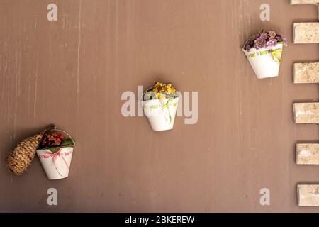 flowerpot-looking wall ornament hanging on a wall with pink, yellow and red artificial plant Stock Photo