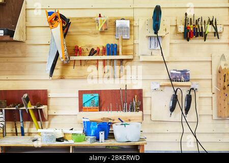 Tools hanging on the wall in a carpentry workshop. Saws, screwdrivers, jigsaws, hammers, drills, etc. Workshop scene Stock Photo