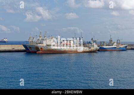 Deep Water Trawlers and General Cargo Vessels streaked with Rust, double and Triple Berthed alongside the Outer Breakwater of Las Palmas. Stock Photo