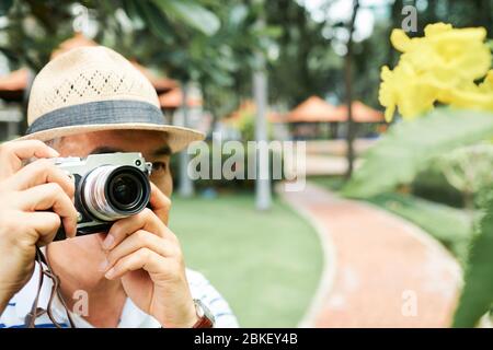 Chinese senior man walking in park and taking photos of trees and flowers Stock Photo