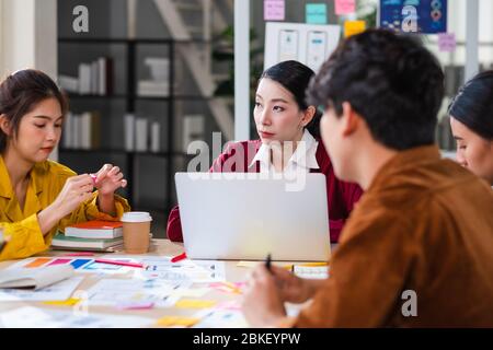 ux developer and ui designer brainstorming about mobile app interface wireframe design on meeting table with customer brief and color code at modern o Stock Photo