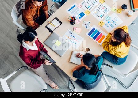 top view ux developer and ui designer presenting mobile app interface with success growth income graph on tablet in meeting at modern office.Creative Stock Photo