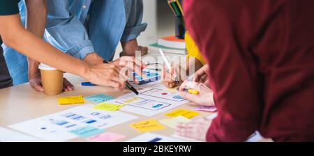Close up ux developer and ui designer brainstorming about mobile app interface wireframe design on table with customer brief and color code at modern Stock Photo