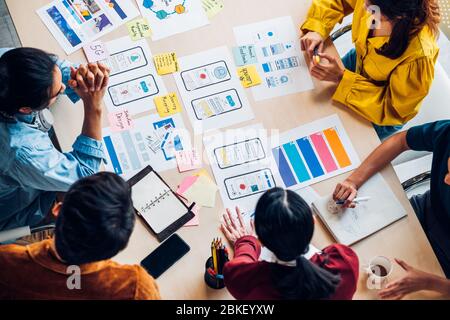 top view asian ux developer and ui designer brainstorming about mobile app interface wireframe design on table with customer brief and color code at m Stock Photo