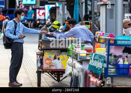 Thai street trader and customer wearing face mask during Covid 19 epidemic, Bangkok, Thailand Stock Photo