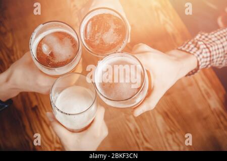 Cheerful and happy old friends are drinking draft beer at pub bar clink glasses. Top view. Friendship concept. Stock Photo