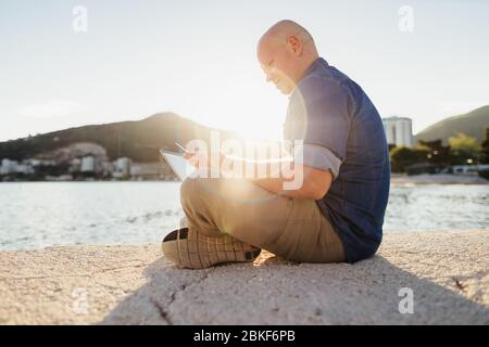 man travel and using laptop at seaside. Self employed man travel and consulting through internet. Holiday maker travel and using internet connection o Stock Photo