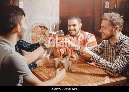Cheerful and happy old friends are drinking draft beer at pub bar. Friendship concept. Stock Photo
