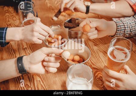 Close up Assorted beer snacks in restaurant. Men hands demonstrated tasty delicious cheese boals in sauce Stock Photo