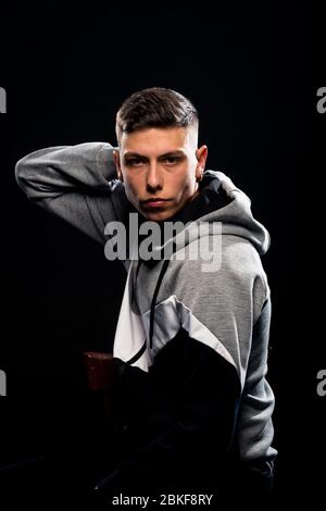 Good looking casual man wearing tracksuit against black wall Stock Photo