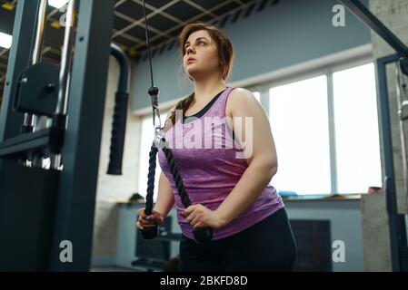 Overweight woman doing stretching exercise in gym Stock Photo