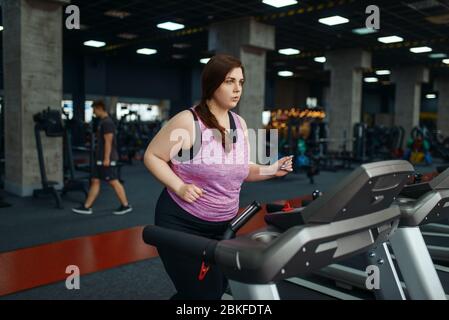 Overweight woman, exercise on treadmill in gym Stock Photo