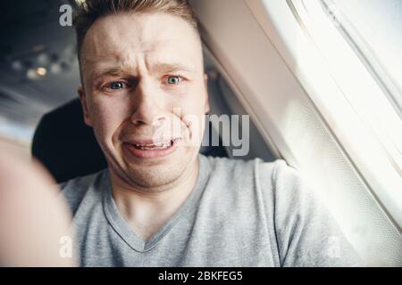 Passenger man in plane clutches his head, afraid of heights and flight. Scream and cry expression. Stock Photo