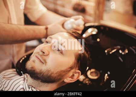 Close up Hairdresser man washing beard client head at Barber shop. Concept haircare Stock Photo