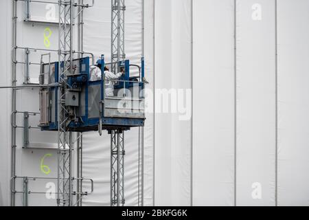 Oberhausen, Germany. 04th May, 2020. Workers travel up the scaffolding with an elevator. The gasometer in Oberhausen is wrapped in a 30,000 square meter facade scaffold for the duration of renovation work. The facade scaffolding will be enclosed piece by piece with a light-colored tarpaulin, which will ensure that the paint and metal residues that are left over from the blasting of the envelope remain on the construction site. The gasometer is expected to be completely covered from June to August. The next exhibition is planned for spring 2021. Credit: Fabian Strauch/dpa/17�Թ����� Live News Stock Photo