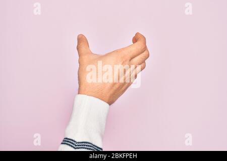 Hand of caucasian young man showing fingers over isolated pink background holding invisible object, empty hand doing clipping and grabbing gesture Stock Photo