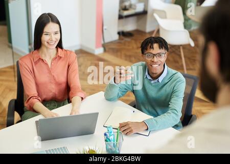Modern young business people having lively discussion during meeting, high angle over-the-shoulder shot Stock Photo