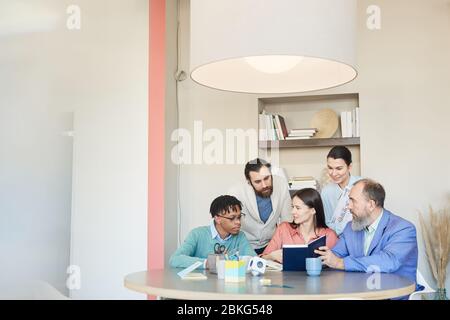 Group of five modern office workers gathered together discussing issues of new big project, copy space Stock Photo