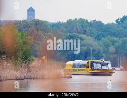 04 May 2020, Brandenburg, Potsdam: The water taxi 3 runs on the Havel or the Tiefen See from the pier Park Babelsberg in the direction of the Glienicke Bridge. Since a few days the yellow ships are again in regular service between Sacrow and Forsthaus Templin. There are 13 stations, bicycles can be taken along. Due to the danger of corona, passengers must wear a mouth-and-nose cover on board and maintain a minimum distance of 1.5 metres. Due to the restrictions, the eight passenger ships of the White Fleet are still lying in the technical harbour waiting for take-off. Photo: Soeren Stache/dpa-
