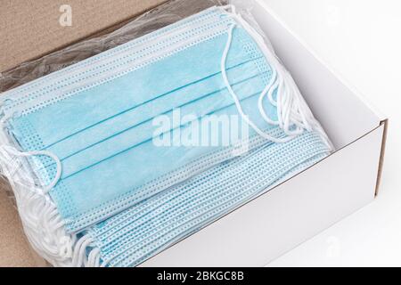 Package of surgical face masks with rubber ear straps in cardboard box. Close-up view of large lot masks in polyethylene packing, ready for delivery Stock Photo