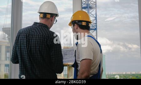 Engineer and worker looking at blueprint. Stock Photo