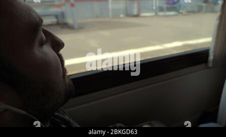 Long way. Man sleeping in the train. People standing behind the Stock Photo