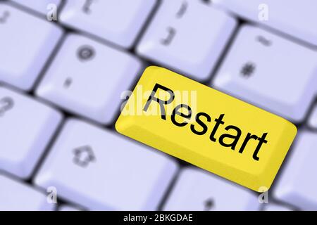 A keyboard with the word RESTART on a yellow enter key on a blurred background of keys. England, UK, Britain Stock Photo