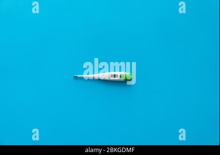 Digital body thermometer lying on a blue background. Medical thermometers. Stock Photo